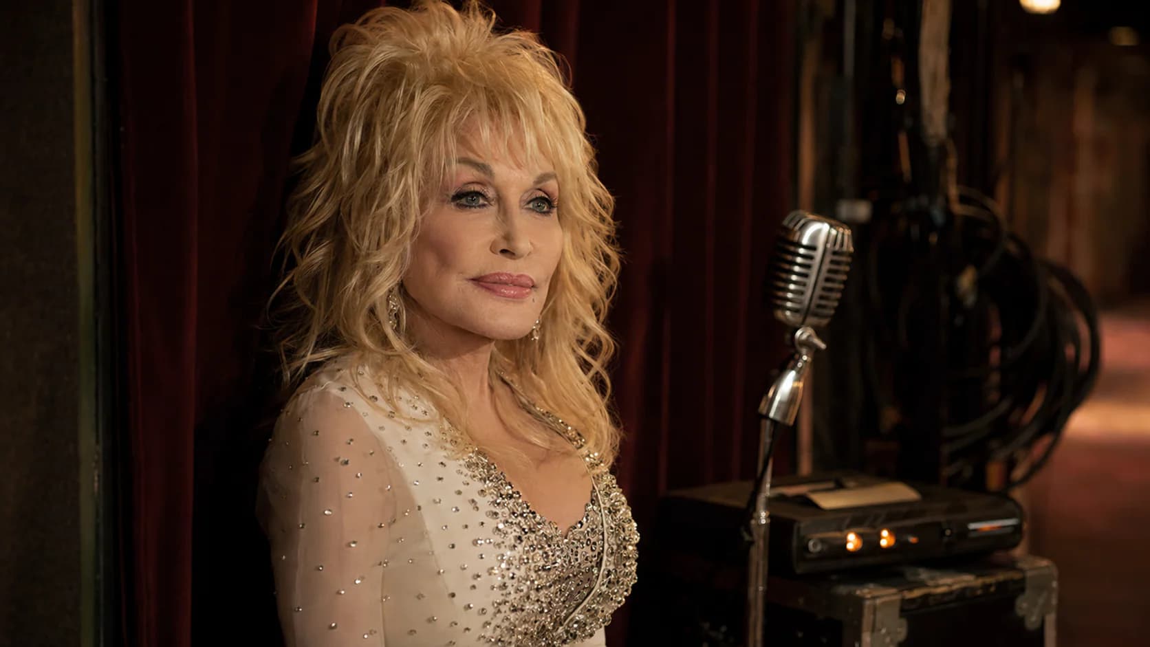 Dolly Parton remembered in a respectful Nashville backstage portrait with a vintage microphone and warm theatrical lighting.